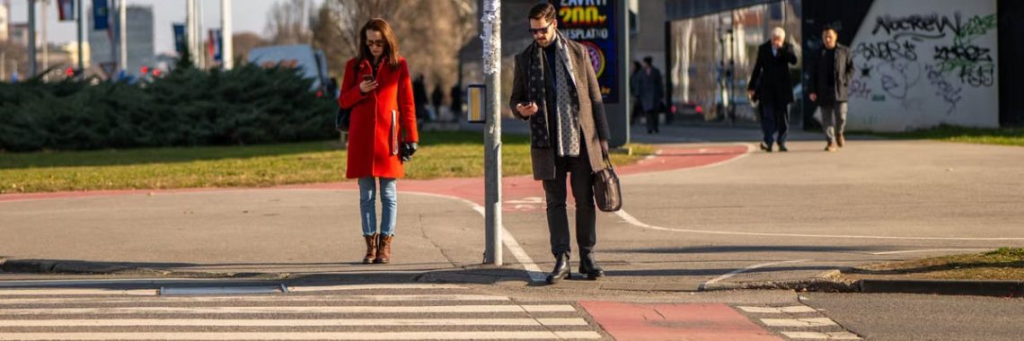 Two adults crossing a street in Zagreb, captured during daylight on a clear day.